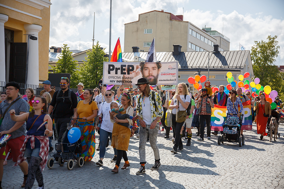 Aikuisia ja lapsia pridekulkueessa.